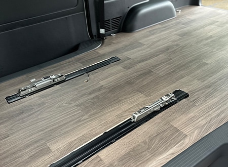 厳選した木目調の床材と、シートや荷物の固定に対応する多機能レールシステムを備えたカスタムバンの後部荷室