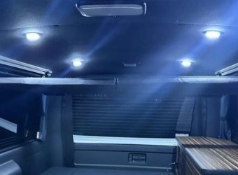 ハイエース車内の間接照明。天井のLEDダウンライトと木目調の収納ユニットが落ち着いた雰囲気を演出